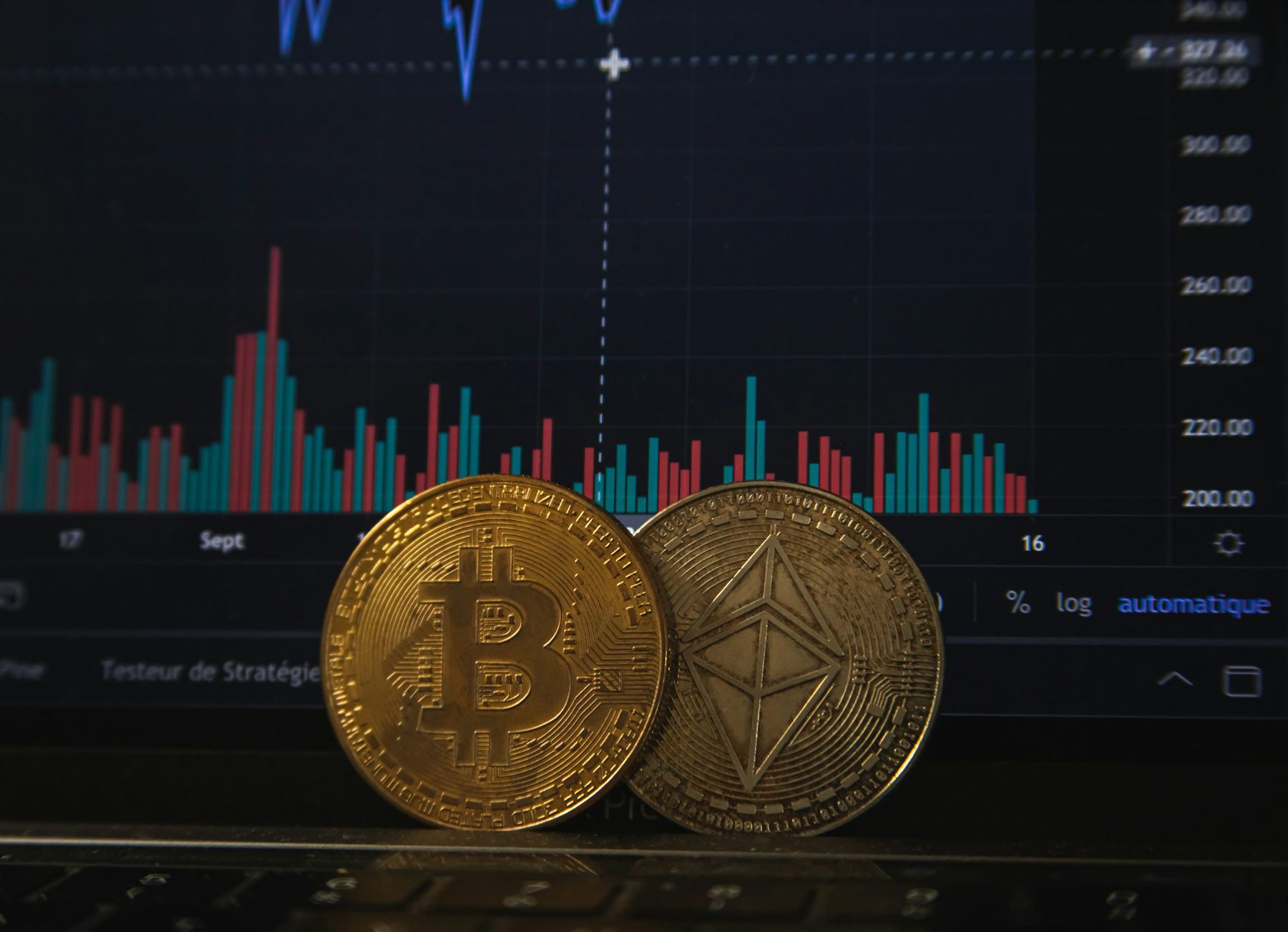 Bitcoin and Ethereum coins in front of a cryptocurrency trading chart