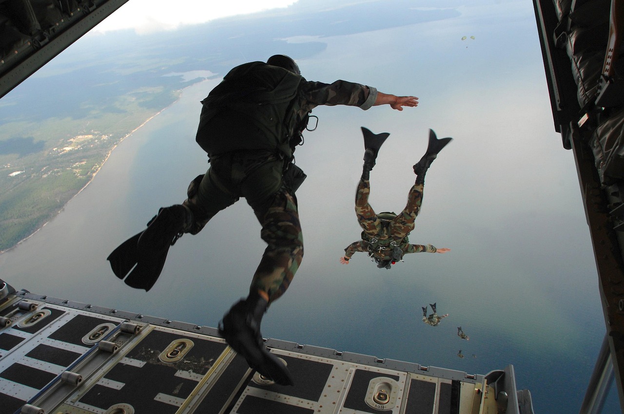 Military parachutists jumping from an aircraft over water