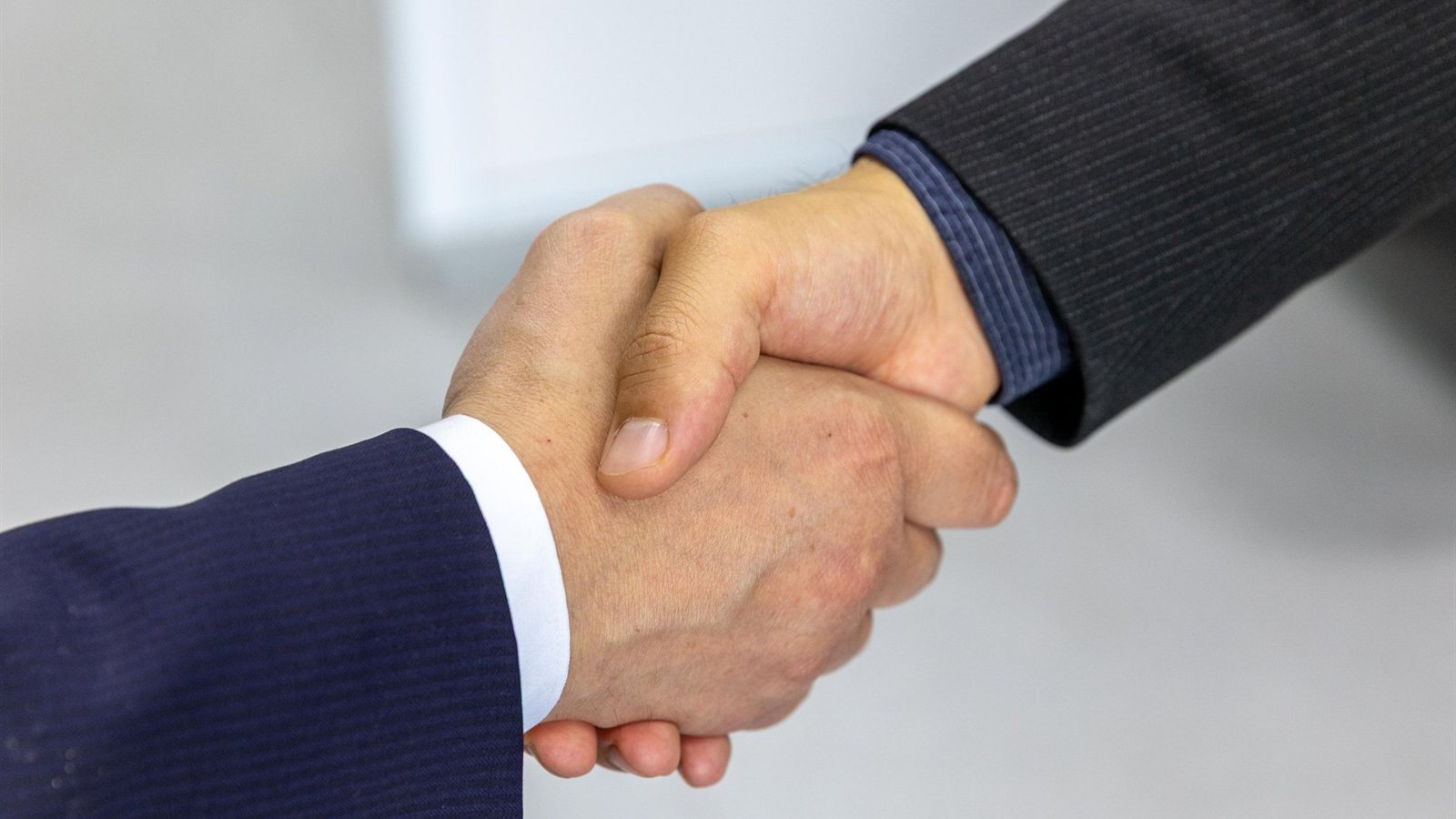 Two people shaking hands after a supplier agreement, the kind of relationship a risk register tracks